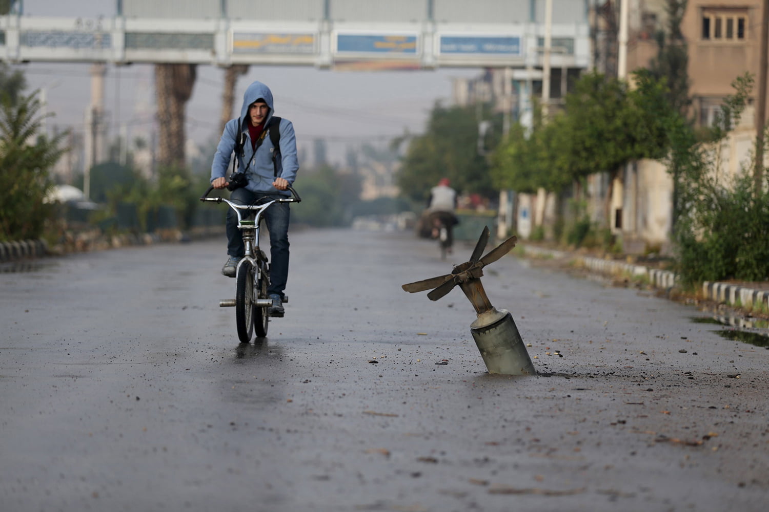 A resident rides his bicycle near what activists said was an  exploded cluster bomb shell in the town of Douma, eastern Ghouta in Damascus